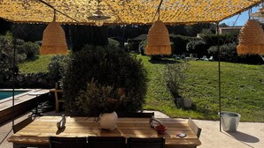 An outdoor patio area with a wooden table, a potted plant, and a hanging light fixture.