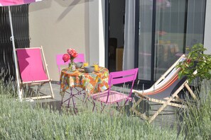 Une terrasse extérieure avec une table, des chaises et un hamac.