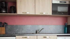 Una cocina con armarios de madera, microondas, cafetera y lavamanos.