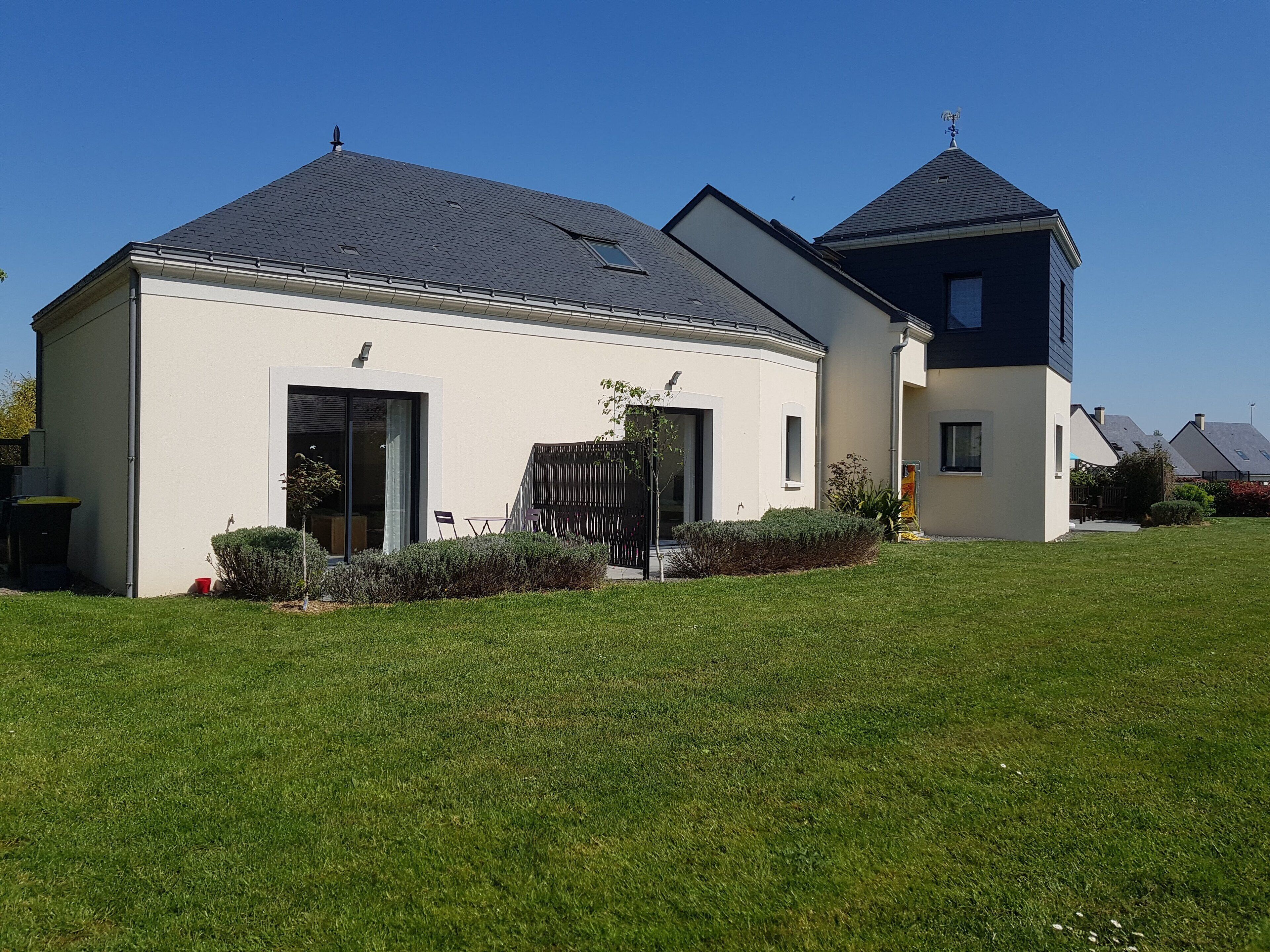 Une maison moderne à deux étages, dotée d  ’un toit plat et d’un petit garage attenant.