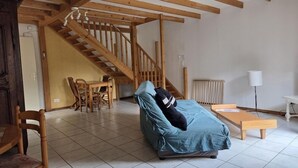 A room with a bed, a wooden table, a chair, a staircase, and a radiator.