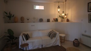 A cozy living room with a sofa, a small table, and decorative items on shelves.