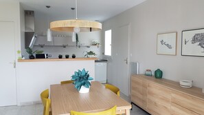 Cozinha moderna com armários brancos, bancada de madeira e luminária pendente.