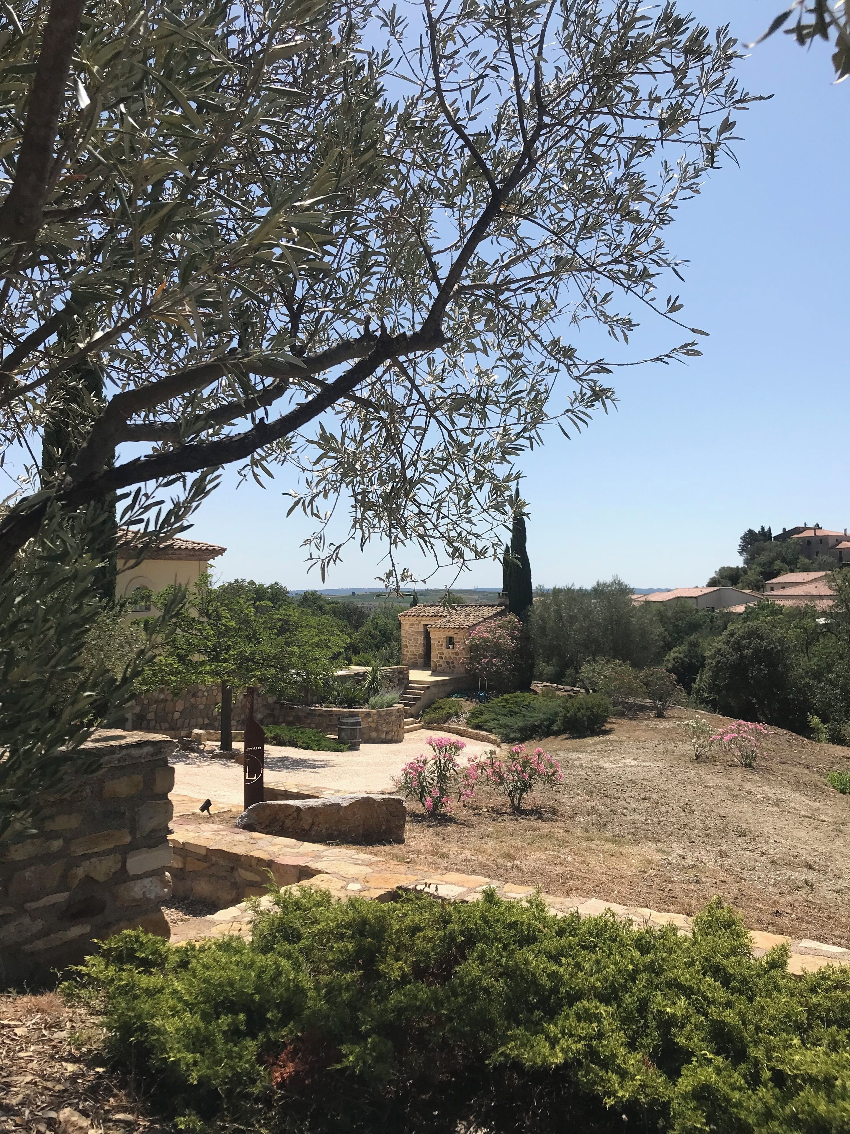 A garden with stone structures, a small building, and a view of distant houses.