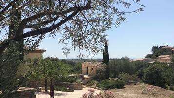 A garden with stone structures, a small building, and a view of distant houses.