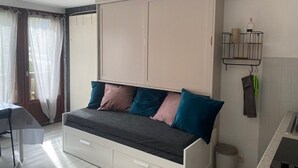 A bedroom with a bed, a desk, and a window with curtains.
