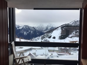 Un balcon offrant une vue sur des montagnes enneigées et sur une ville située en contrebas.