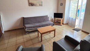A living room with a sofa, a coffee table, and a television. - The stable, quiet house in the countryside (Quéménéven)