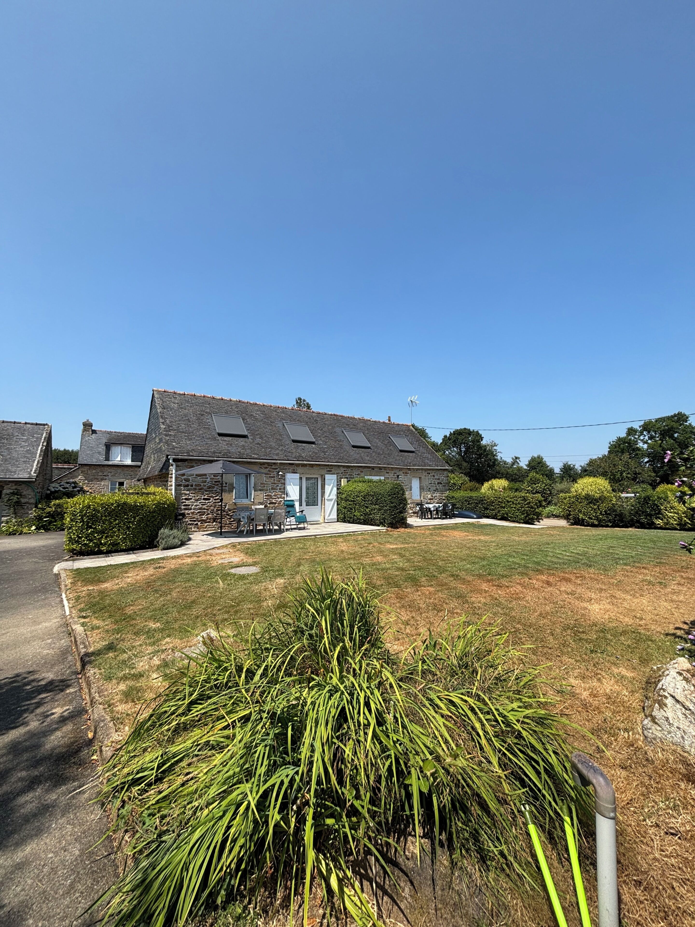 A residential area with stone houses, a well-maintained lawn, and a clear sky.
