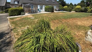 A residential area with stone houses, a well-maintained lawn, and a clear sky. - The stable, quiet house in the countryside (Quéménéven)