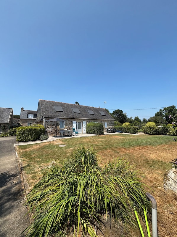 A residential area with stone houses, a well-maintained lawn, and a clear sky.