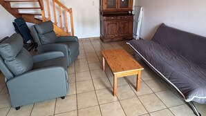 A living room with a sofa, a wooden coffee table, a cabinet, and a staircase. - The stable, quiet house in the countryside (Quéménéven)