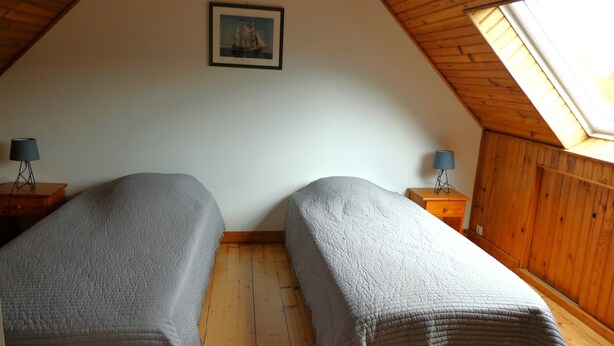 A bedroom with two beds, wooden floors, a skylight, and a framed picture on the wall. - The stable, quiet house in the countryside (Quéménéven)