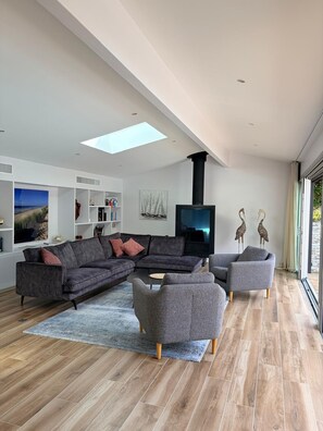 A modern living room with a sectional sofa, armchairs, a flat-screen TV, and a fireplace. - Very beautiful villa 9/10 pers Lacanau Ocean, facing golf (Lacanau)