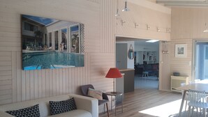 A modern living room with a white sofa, a round coffee table, and a large painting of a pool.