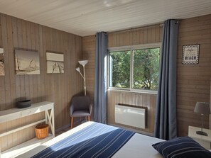 Un dormitorio con cama, escritorio, silla, ventana con cortinas y radiador.