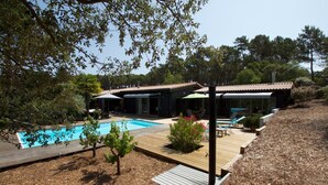 A modern house with a swimming pool, wooden deck, and a garden area.