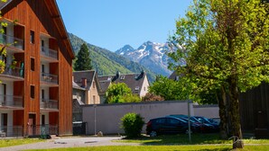Ein mehrstöckiges Holzgebäude mit Balkonen, einem Parkplatz und Blick auf schneebedeckte Berge.