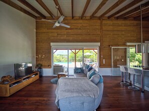 A spacious living room with a large sofa, a television, and a ceiling fan. - SOL Y LUNA • 3 bedrooms, pool, and the beach within walking distance (Sainte-Anne)