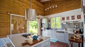 Une cuisine moderne avec des poutres en bois, un îlot central et une vue sur l’extérieur.