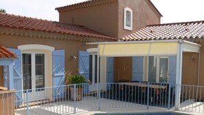 Una piscina con una veranda coperta, un tavolino e sedie.