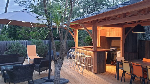 Une terrasse extérieure avec des meubles en bois, un coin bar et une cuisine.