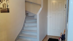 A staircase leading to an upper floor, a white door, and a small table with items on it. - Luxury house close to Disney & Paris wifi & breakfast free.  (Noisiel)