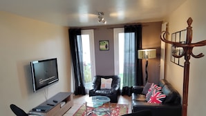 A living room with a flat-screen TV, leather sofas, a glass coffee table, and a patterned rug. - Luxury house close to Disney & Paris wifi & breakfast free.  (Noisiel)