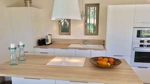 Una cocina moderna con armarios blancos, encimera de madera, horno Bosch y un cuenco de fruta.