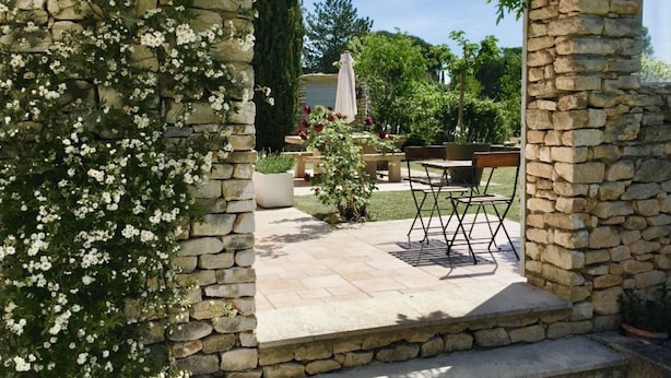 Un arco de piedra que da a un patio con mobiliario exterior y un jardín.
