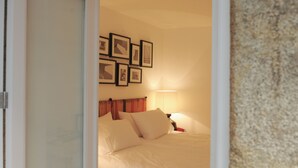 Ein Schlafzimmer mit Bett, Kissen, einem Nachttisch, einer Lampe und gerahmten Bildern an der Wand.