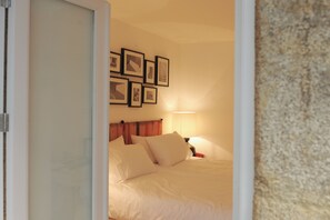 A bedroom with a bed, pillows, a nightstand, a lamp, and framed pictures on the wall.