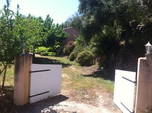 Un cancello chiuso da un muro, con un cancello bianco, un pilastro in pietra e un piccolo lanternino bianco in cima.