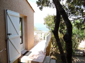 Una proprietà costiera con una porta bianca, un balcone con ringhiera bianca e vista sul mare.