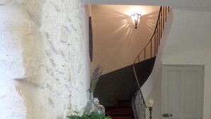 Escadaria com corrimão de madeira e luminária fixada na parede.