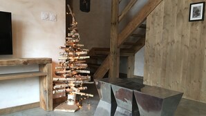 A modern interior with a wooden staircase, a fireplace, and a unique light installation. - 1/2 Chalet close to the center, quiet, private parking, 4 bedrooms 2 bathrooms (Chamonix-Mont-Blanc)