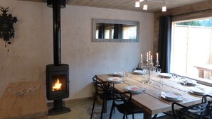 A dining area with a wood-burning stove, a mirror, and candles on the table. - 1/2 Chalet close to the center, quiet, private parking, 4 bedrooms 2 bathrooms (Chamonix-Mont-Blanc)