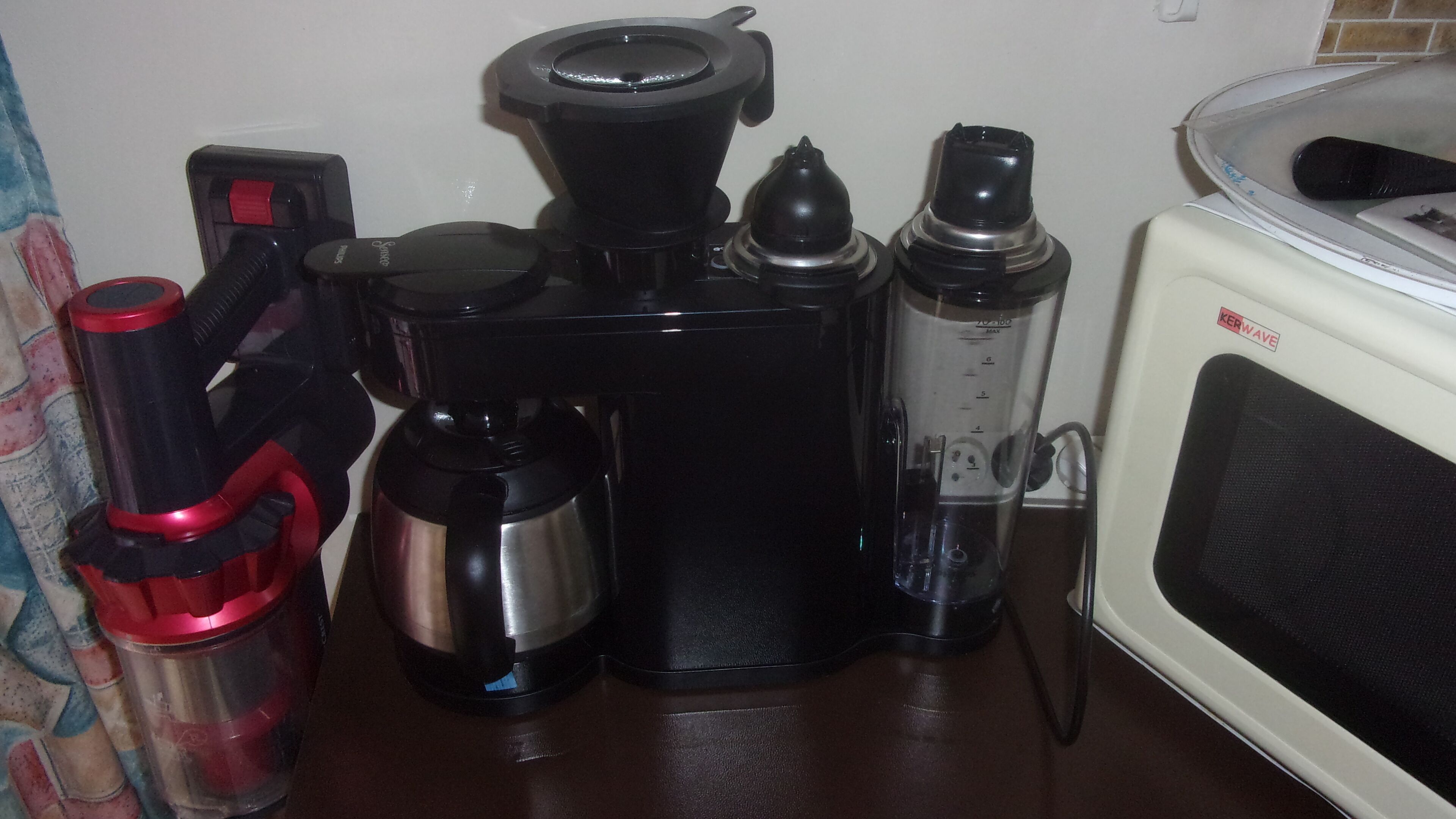 Una cocina equipada con cafetera, licuadora y microondas.