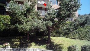 A multi-story residential building with balconies, surrounded by trees and a grassy area. - Residence A. LE CAPUCIN, N ° 68 Apartment 4 people facing LUGE TENNIS COURTS (Mont-Dore)