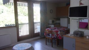 A small, compact kitchen with a dining table, a microwave, and a television. - Residence A. LE CAPUCIN, N ° 68 Apartment 4 people facing LUGE TENNIS COURTS (Mont-Dore)
