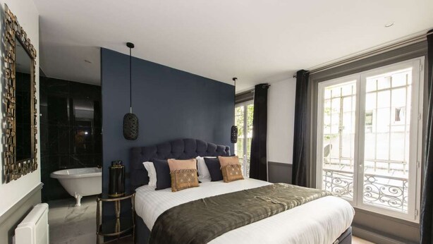 Ein Schlafzimmer mit einem großen Bett, einem Nachttisch, einer modernen Lampe und Blick durch ein Fenster.