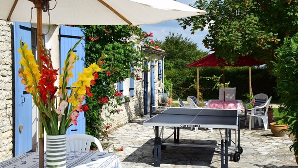 An outdoor patio with a ping pong table, white chairs, and a table with a checkered tablecloth. - House, private pool near sea Charente-Maritime near La Rochelle, Cognac (Tonnay-Boutonne)