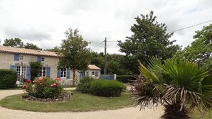 A house with a gravel driveway, a garden with flowers, and a palm tree. - House, private pool near sea Charente-Maritime near La Rochelle, Cognac (Tonnay-Boutonne)
