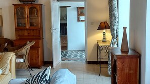 A room with a bed, a wooden cabinet, a lamp, and a view of an open door leading to another room. - House, private pool near sea Charente-Maritime near La Rochelle, Cognac (Tonnay-Boutonne)