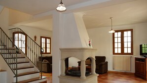 A spacious living room with a fireplace, a staircase, and a television. - Holiday villa with pool Les Vignes - bastides-du-luberon.com (La Tour-D'aigues)