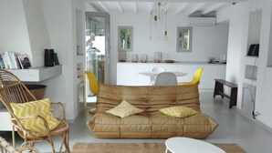 A modern living room with a brown sofa, yellow and white patterned cushions, wicker chairs, and a white coffee table. - Villa with an exceptional view of the sea and the bay of Agay (Saint-Raphaël)
