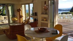 A modern living room with a glass door leading to an outdoor patio. - Villa with an exceptional view of the sea and the bay of Agay (Saint-Raphaël)