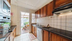 A modern kitchen with wooden cabinets, a stainless steel oven, and a black countertop.