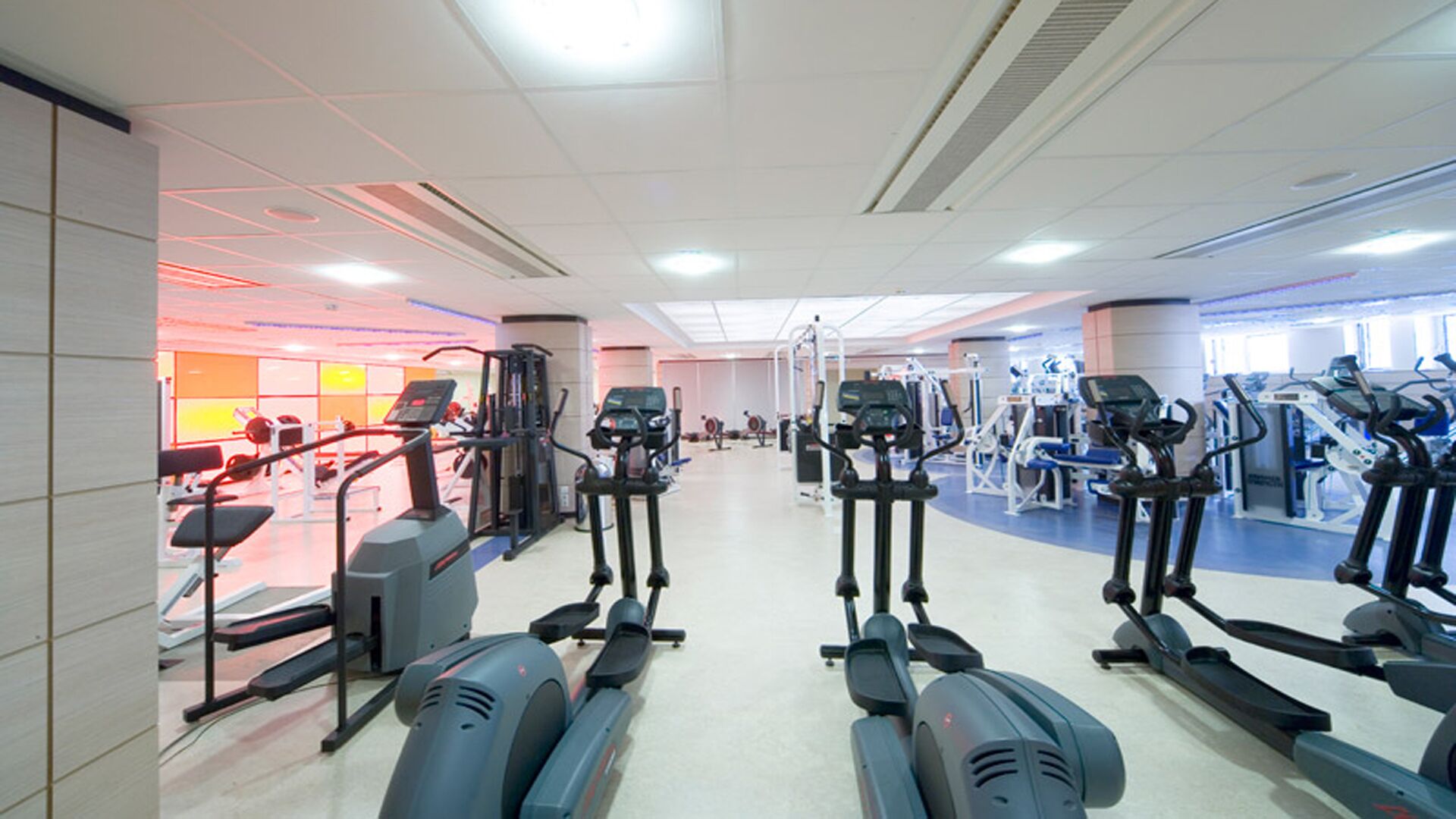 Ein Fitnessstudio mit mehreren Laufbändern, Crosstrainern und Kraftgeräten.