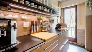 Una cocina moderna con cafetera, juego de cuchillos y varios frascos en estantes.